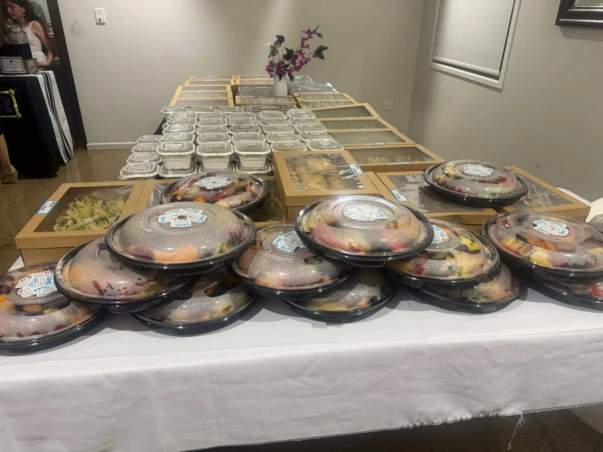 Catering table with prepared bowls and boxed dishes ready to serve