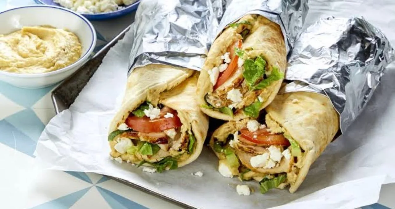 Wrapped kebabs with fresh salad filling arranged on foil
